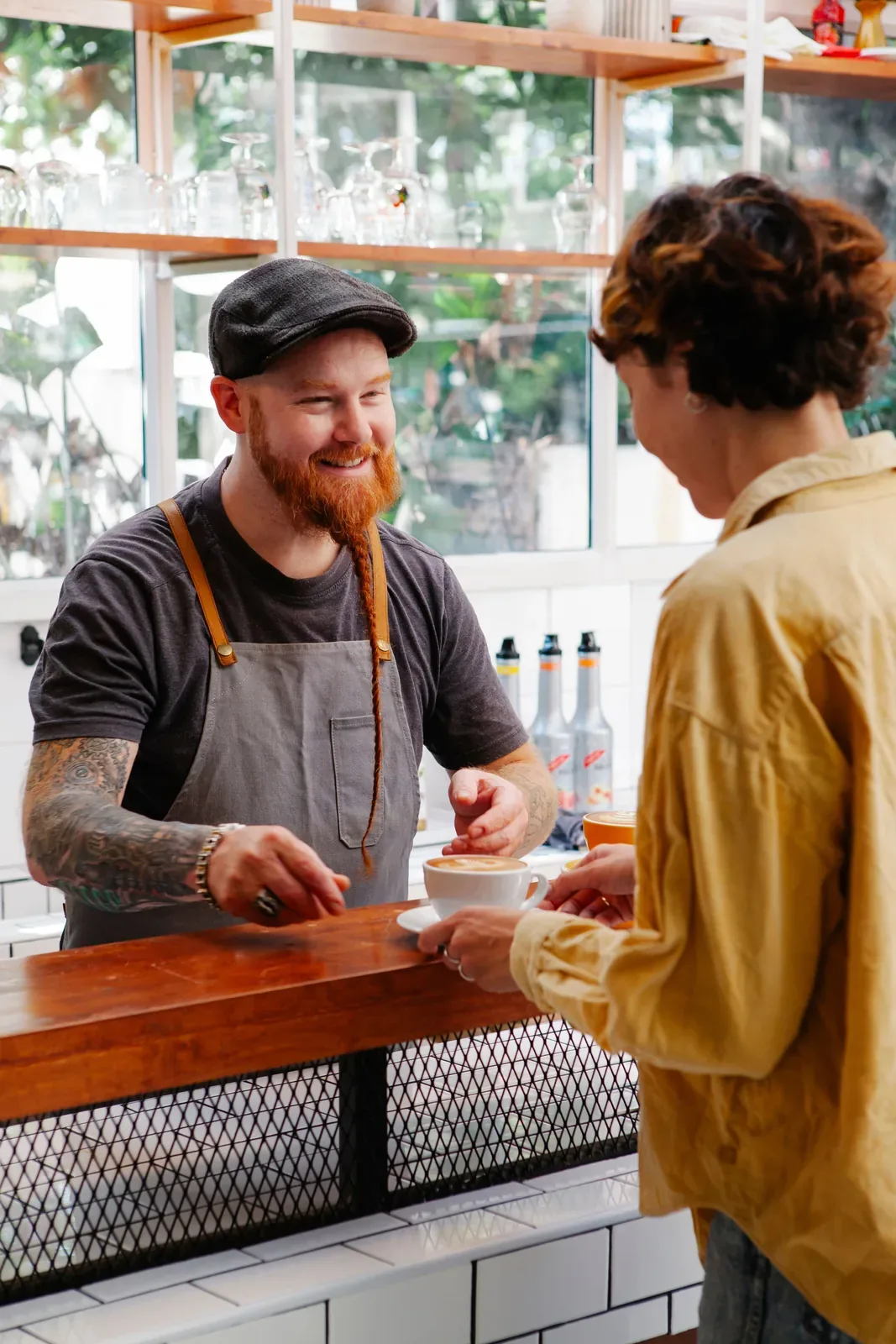 A barista handing a cup of coffee to a guest