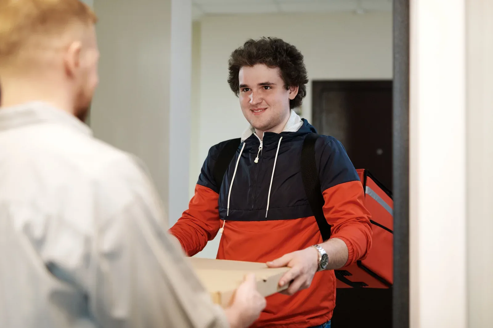 A courier handing a pizza box to a customer