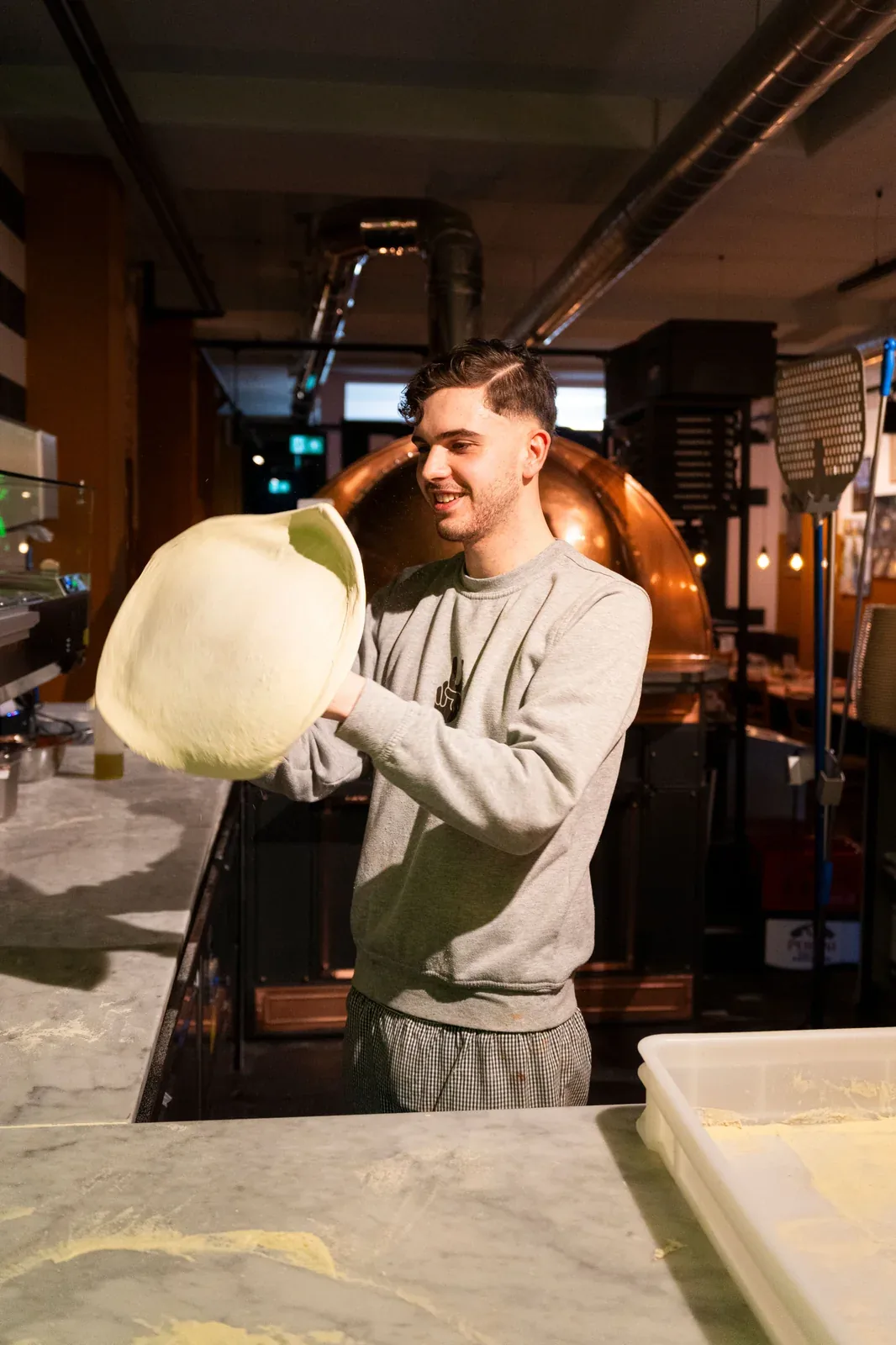 A pizza chef stretching dough in a working pizzeria