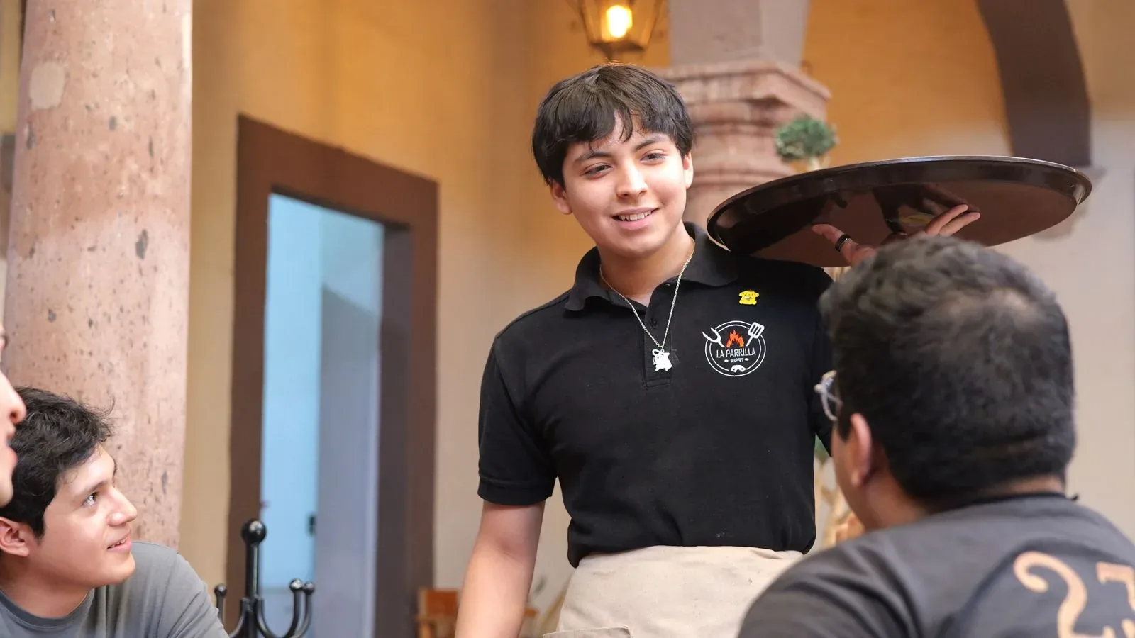 A waiter talking with guests at their restaurant table