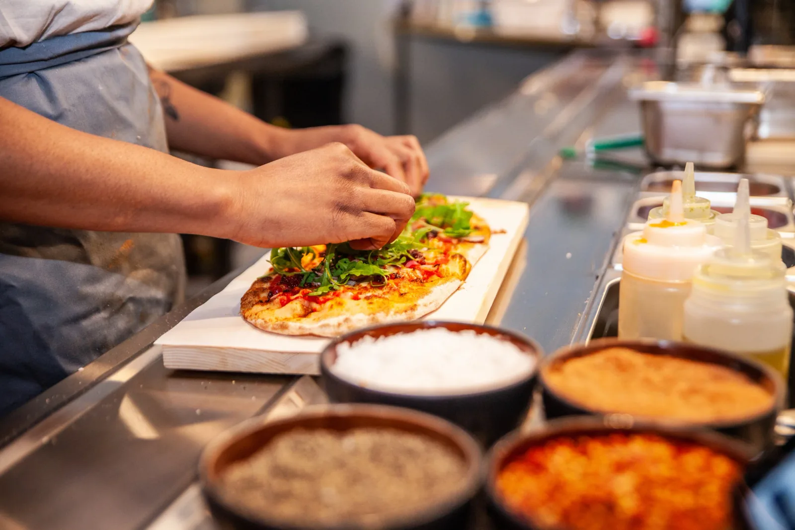 A DIGG team member finishing a pizza at the restaurant counter