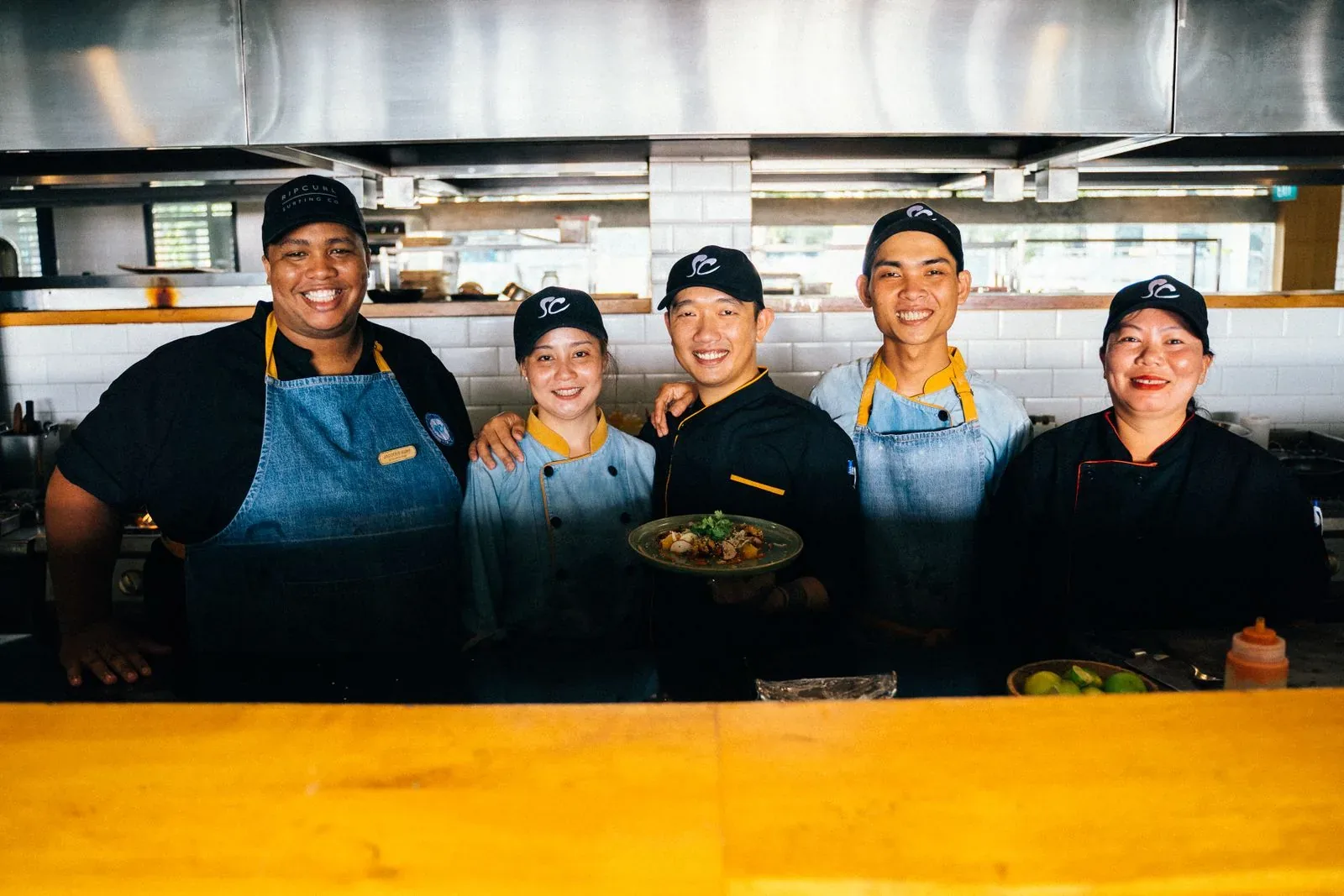 Five members of a restaurant kitchen team smiling together