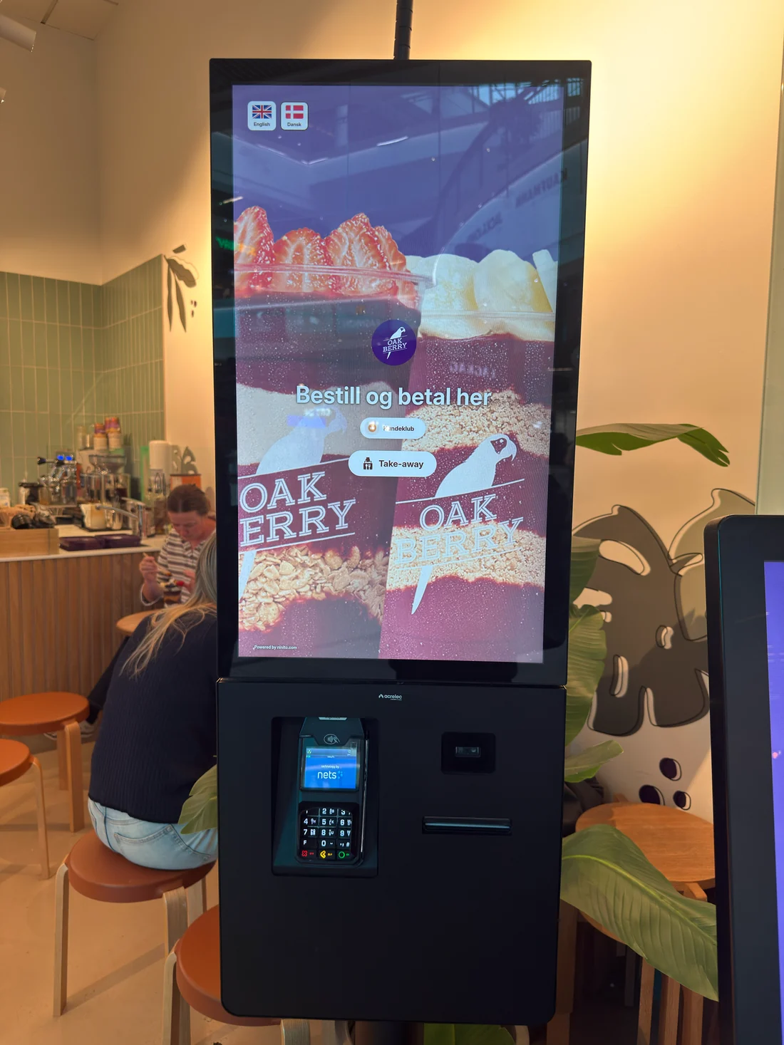 كشك طلب ذاتي مستقل يعرض منتجات Oakberry على شاشة تعلو جهاز الدفع
