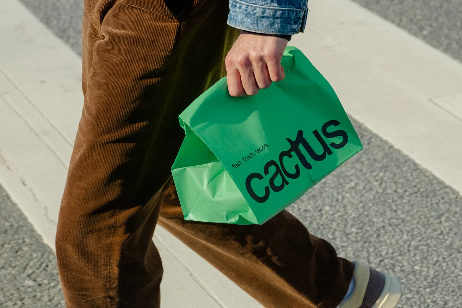 شخص يحمل كيس طلبات خارجية أخضر من Cactus Taco.