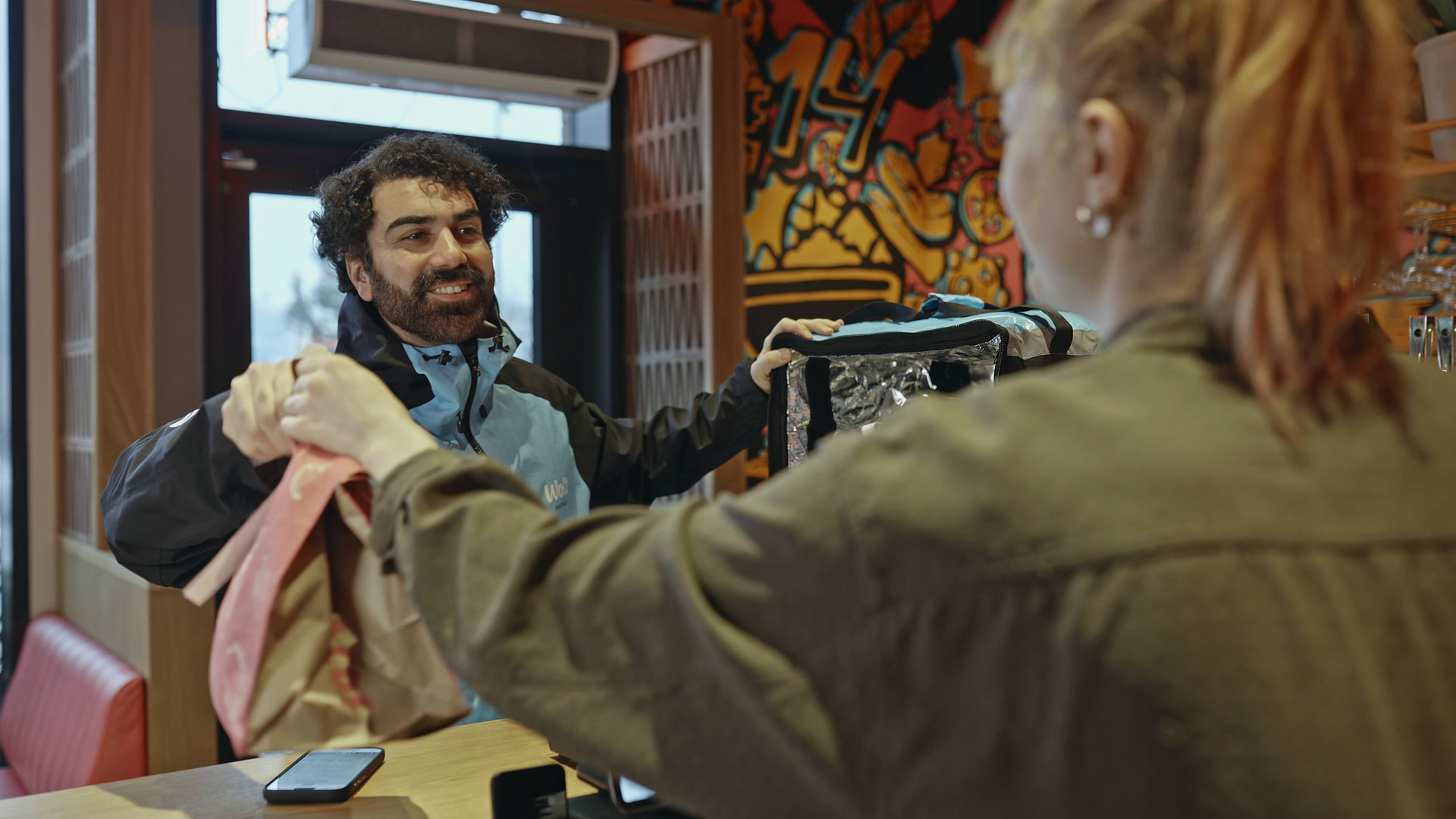En restaurantmedarbejder giver en pakket bestilling til et bud.