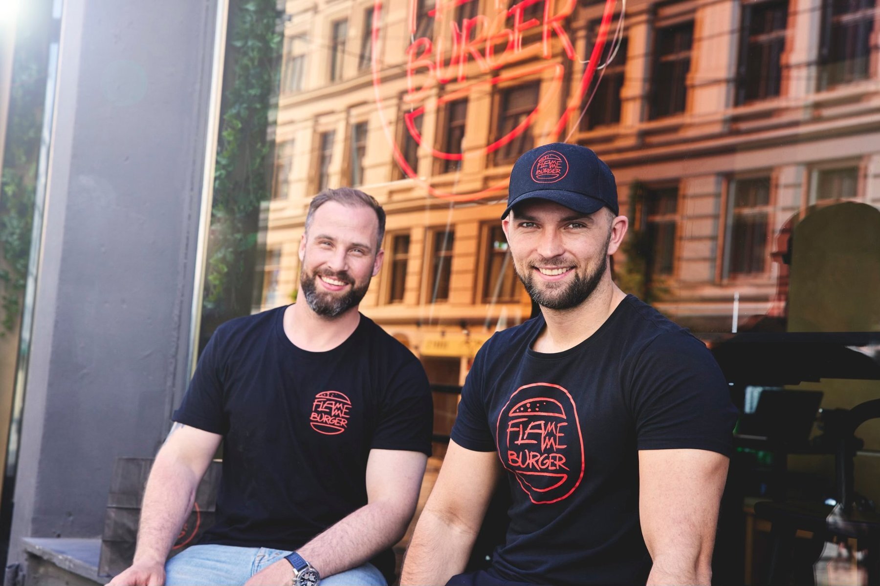 مؤسسا Flamme Burger، Adam Schive Bjerck وØyvind Bøe Dalelv، خارج المطعم مرتديين قميصين يحملان اسم Flamme Burger