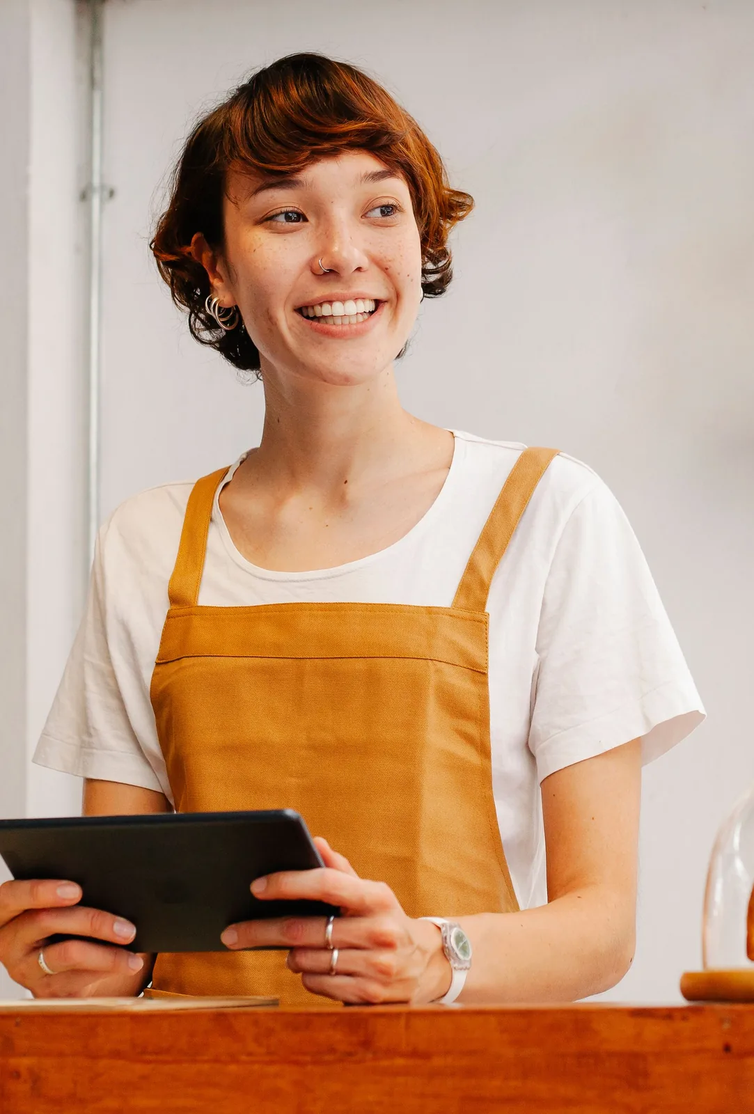 A smiling café worker holding a tablet behind the counter