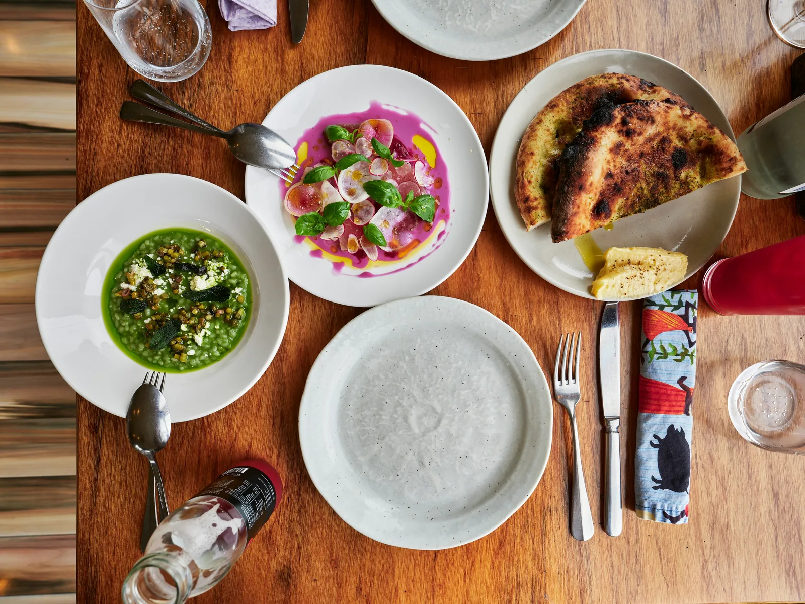 Fargerike restaurantretter, brød og keramikk på et trebord