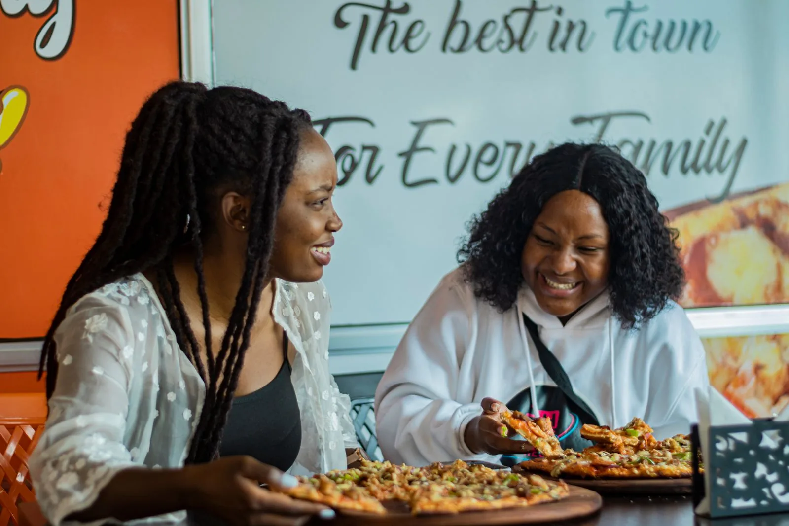 To smilende gjester spiser pizza sammen på en restaurant