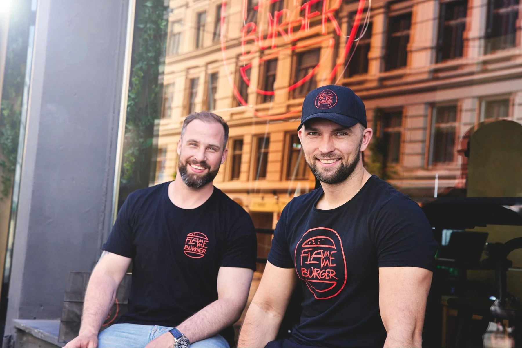 مؤسسا Flamme Burger، Adam Schive Bjerck وØyvind Bøe Dalelv، خارج المطعم مرتديين قميصين يحملان اسم Flamme Burger